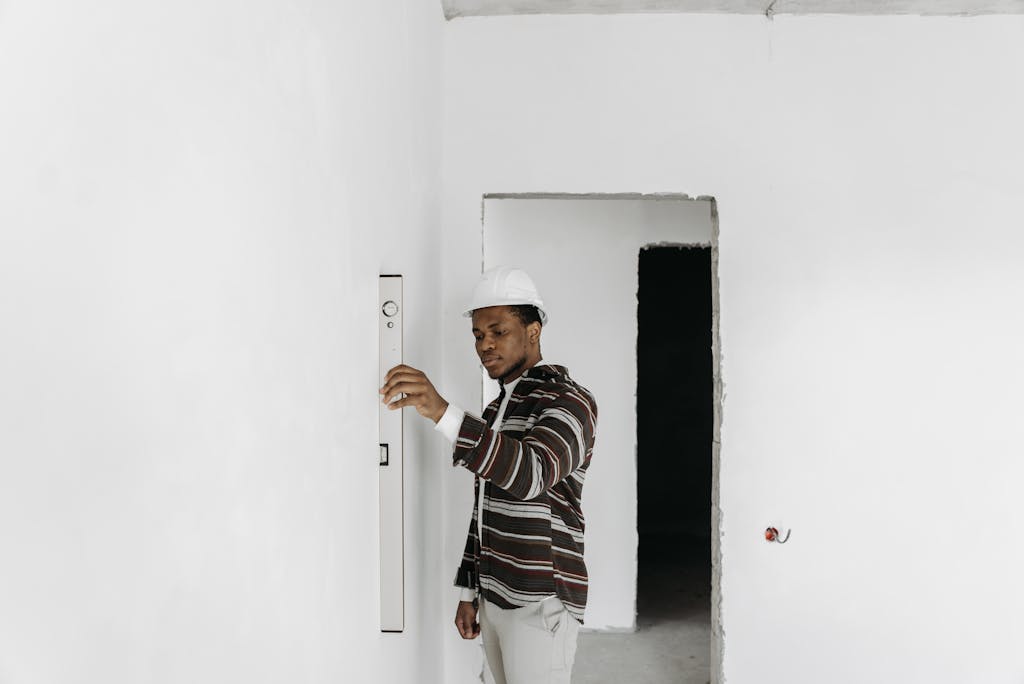 Architect wearing hard hat checks wall alignment in a renovation project.